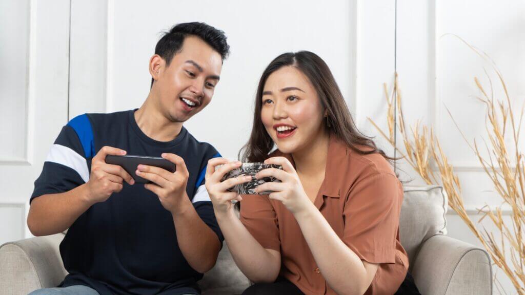 a man and woman sitting on a couch looking at a cell phone